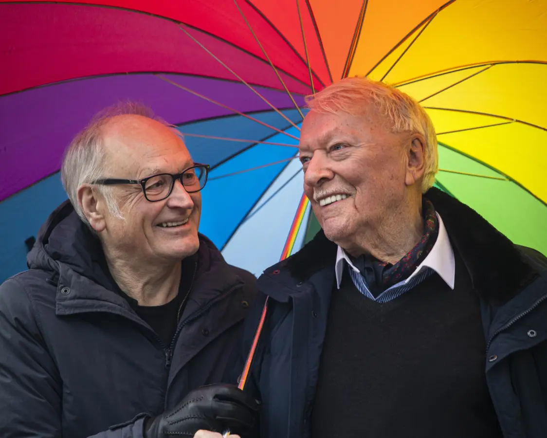 to menn under en regnbuefarget paraply