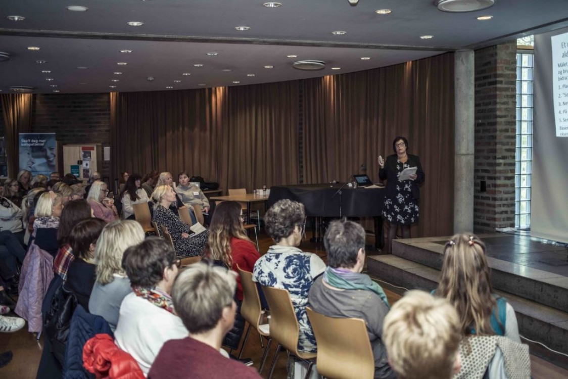Kvinne snakker for forsamling.