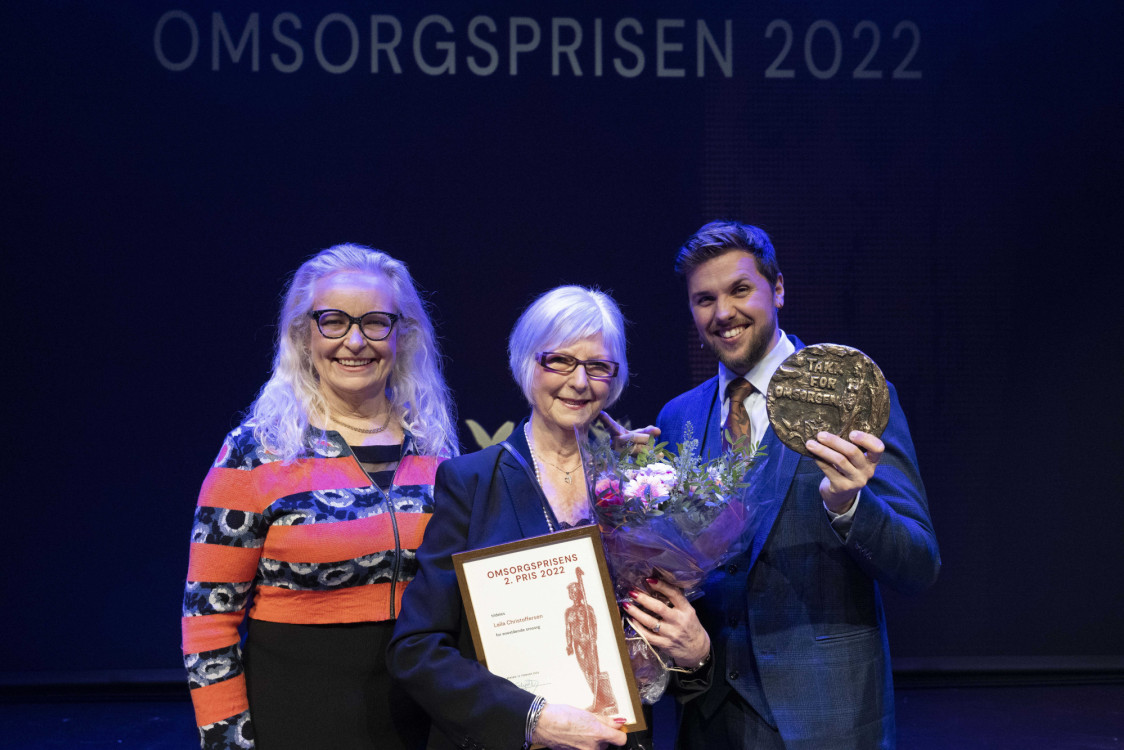 eldre dame mottar blomster og pris og står mellom dame og mann