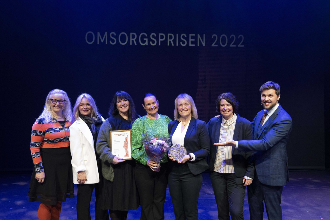 en gruppe mennesker fra Aktivt Plus mottar blomster på en scene