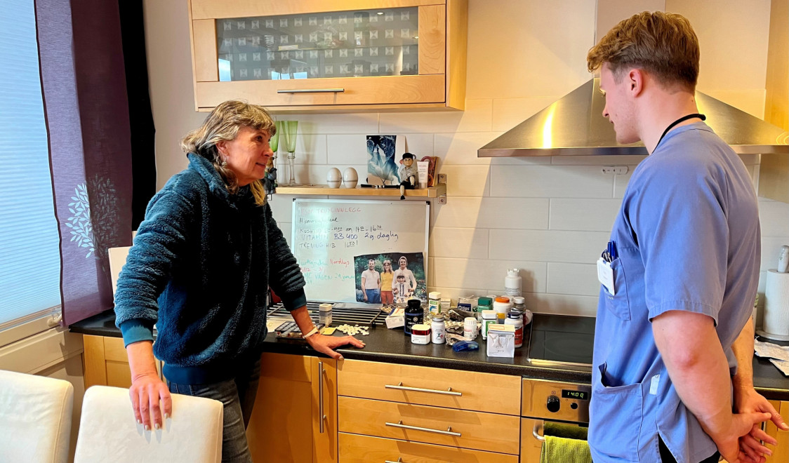 en dame viser sine medisiner til en sykepleier i hjemmetjenesten