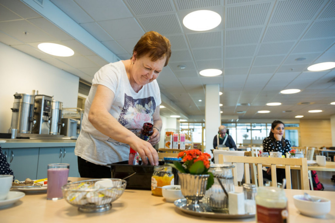Kvinne setter frem pålegg på et bord.