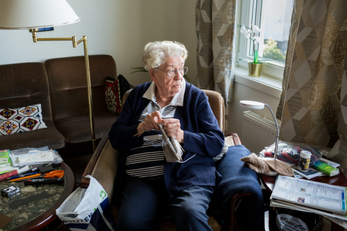 Kvinne strikker og ser ut av vinduet.