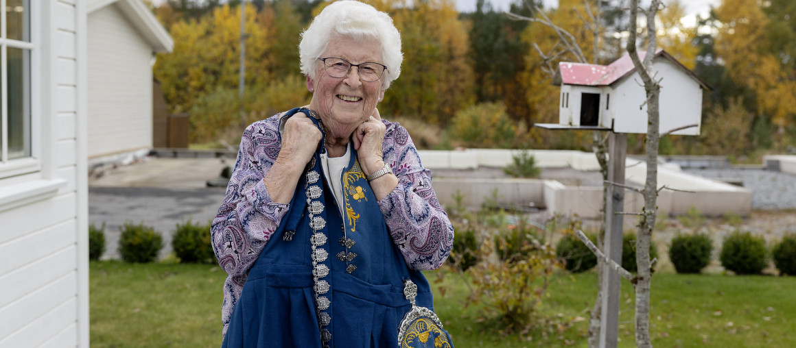 eldre dame holder opp en Vest-Agder bunad