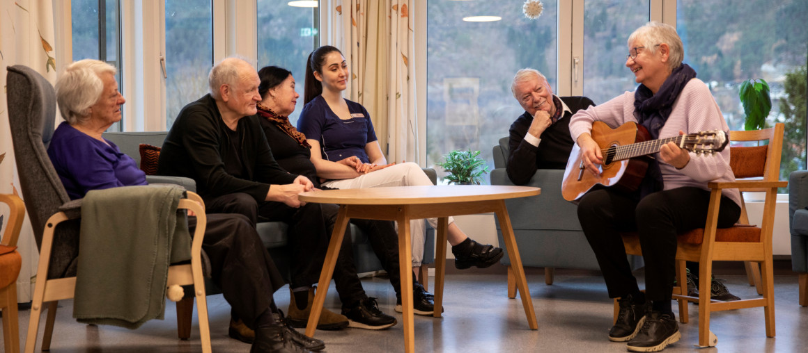 en dame spiller for en gruppe eldre på et sykehjem