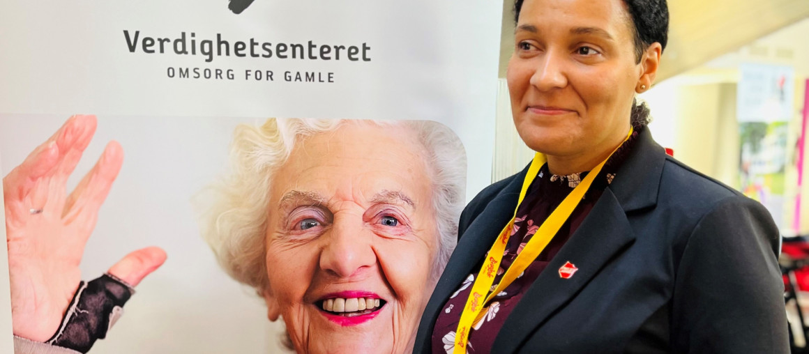 Dame smiler ved en Roll up plakat