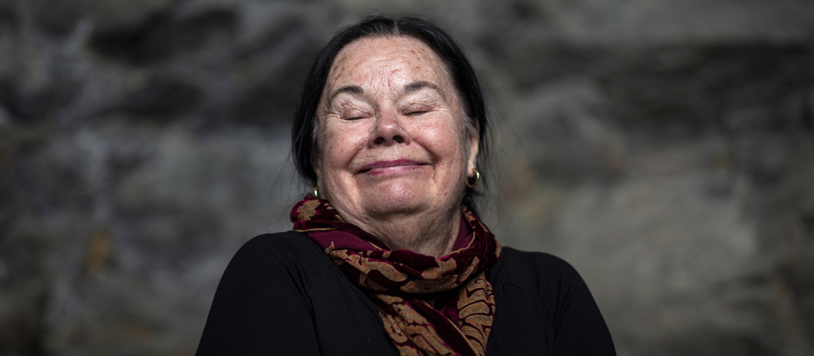 En eldre kvinne lukker øynene og smiler