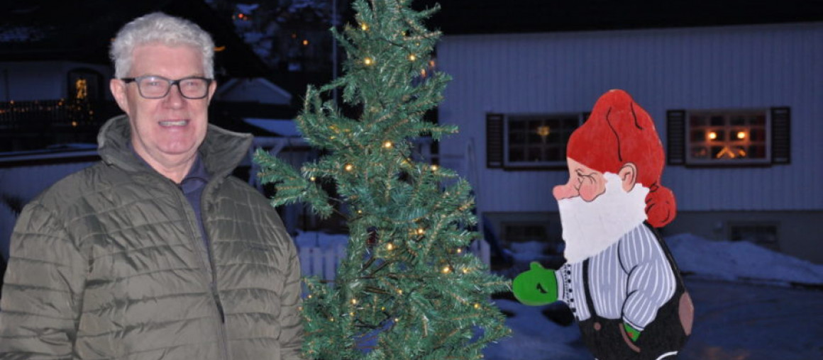 En mann soms smiler, nisse, juletre.