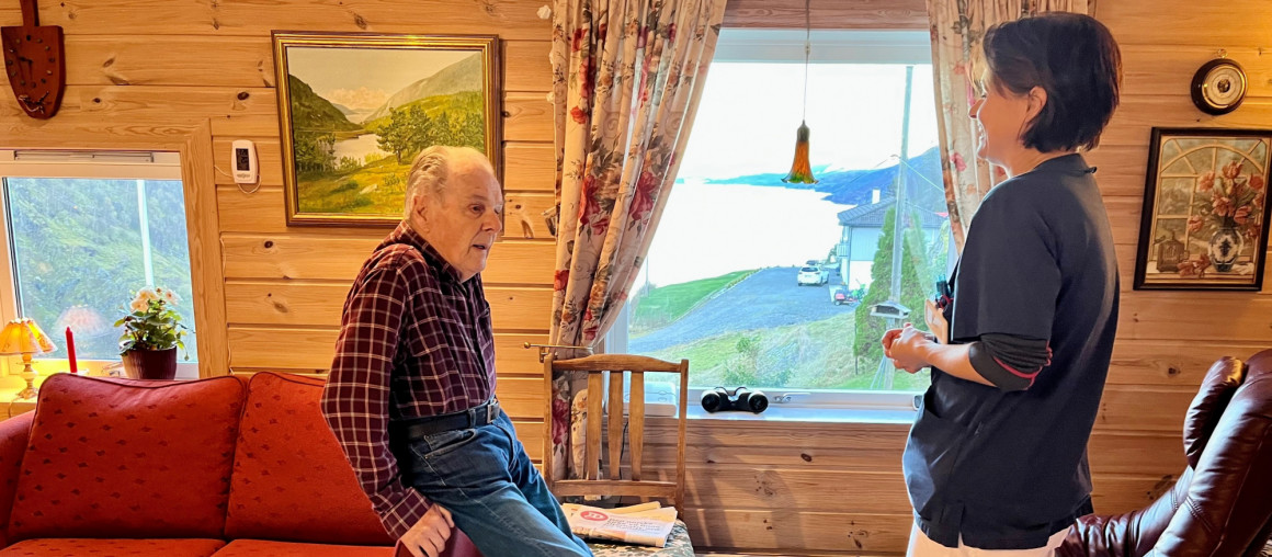 en eldre mann i stua prater sammen med sykepleier