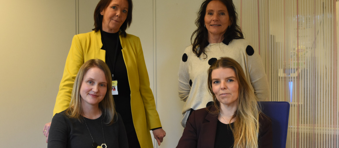 fire smilende damer ser i kamera