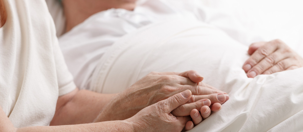 en sykepleier og en eldre dame ser på hverandre og smiler