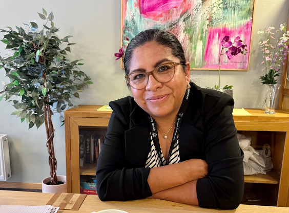 bilde av dame fra Peru som sitter og smiler ved et bord